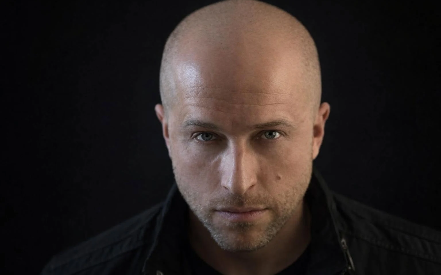 A.Paul in a close black background portrait